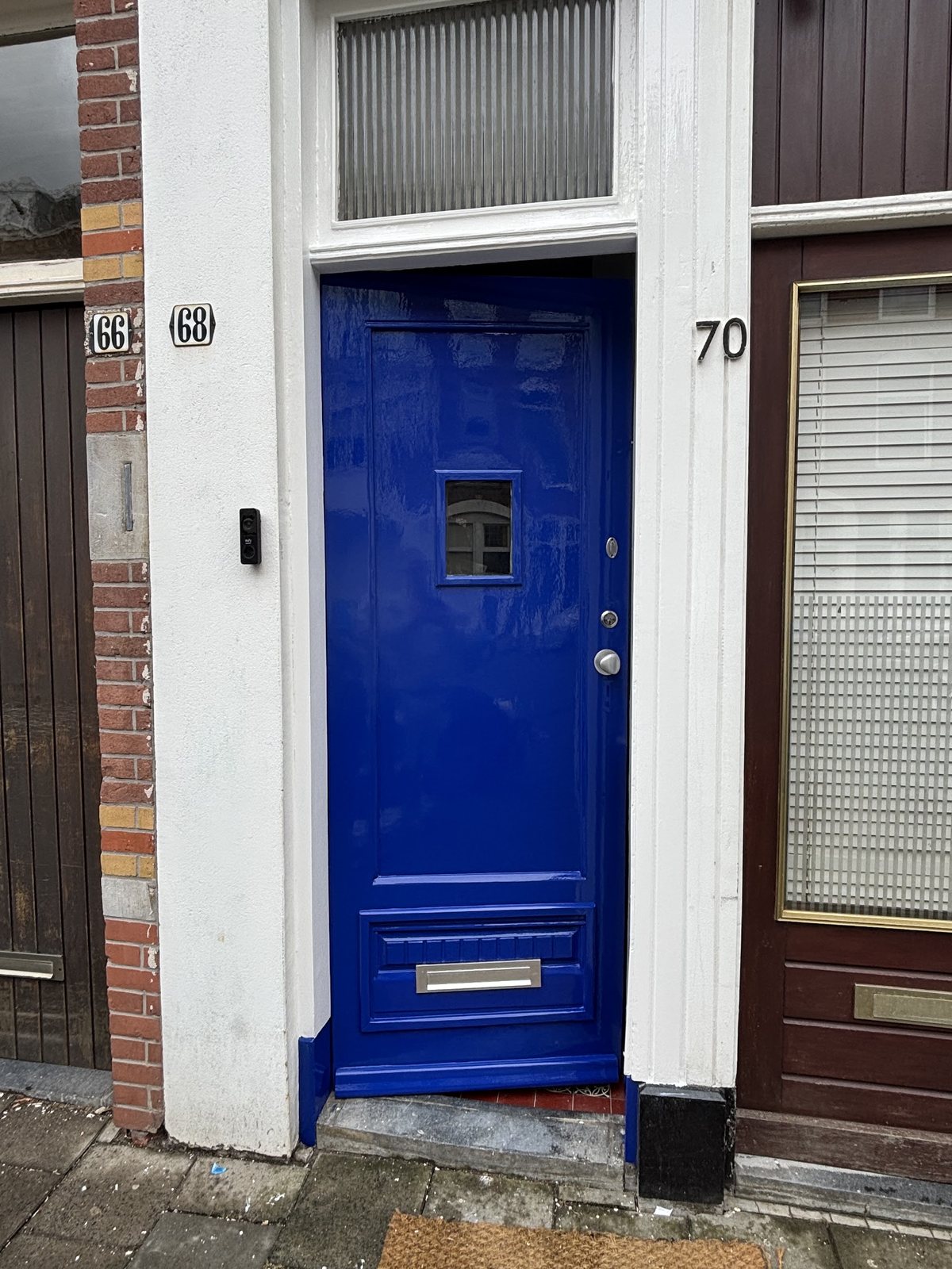 Hoogglans kobaltblauwe voordeur met wit kozijn en een brievenbus